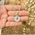 Primo piano di un ciondolo opale su una catena d'argento tenuto da una mano all'aperto - Opale (Ciondolo Solo)