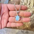 Angel wing opal teardrop pendant necklace with silver chain shown in a detailed hand view - Pendant Only (No Chain) / Opal