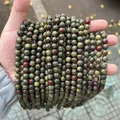 Multiple strands of natural dragon blood jasper round beads held in hand for DIY jewelry - Dragon Blood Stone