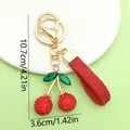 Detailed view of red rhinestone cherry keychain with dimensions 10.7cm x 3.6cm. - Large Cherry with Rope and Rhinestone (ER1867) / 3.6x10.7cm