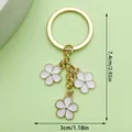 Elegant gold keychain featuring three white enamel flower charms, 7.4cm length dimension - Triple Flower Charm (LS231) / White