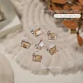 Champagnerfarbenes rechteckiges Kristall-Nagelkunst-Amulett mit kleiner weißer Blume - Rechteck Champagner