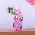 Dettaglio macro di una delicata statuetta di coniglio in cristallo rosa trasparente su legno - Coniglio in Piedi Tutto Rosa
