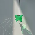 Green translucent butterfly crystal sun catcher pendant hanging in natural sunlight - Brown Rope / Peacock Green