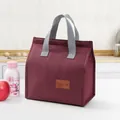 Vertikale isolierte weinrote Lunchtasche mit grauen Griffen und Leder-Aufnäher - Burgunderrot