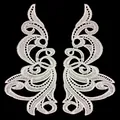 Close-up of white water-soluble lace patches with symmetrical scroll embroidery - White
