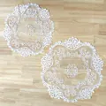 Detailed view of two white circular lace doilies with intricate embroidery on a wooden surface. - Circular 30cm / White
