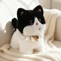 Adorable black and white tuxedo cat plush toy with white lace collar on white sofa - Cow