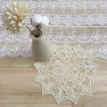 Vista detallada de un elegante posavasos redondo de encaje beige bordado sobre madera rústica - Estilo Carillón de Viento