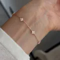 Close-up view of a delicate rose gold four-leaf clover bracelet worn on a wrist. - 925 Silver / Rose Gold