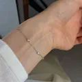 Close-up of minimalist S925 sterling silver thin chain bracelet with bezel-set stones on wrist - 925 Silver / White Gold