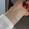 Detailed view of a silver four-leaf clover bracelet with sparkling stones on a wrist. - 925 Silver / White Gold
