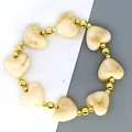 Gedetailleerde weergave van een Franse armband met beige hars hartjes en gouden kralen. - Beige Armband