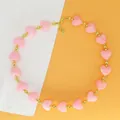 Close-up of pink heart resin beads with gold-tone accents on a sweet style necklace - Pink Necklace