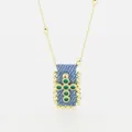 Dettaglio macro di una collana con ciondolo a croce retrò bohémien con zirconi verdi su denim - Verde Scuro (B)