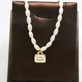 Detailed macro view of a vintage imitation pearl necklace featuring a gold suitcase pendant. - White Suitcase Style / White