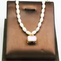 Detailed view of a white pearl necklace with a purple suitcase pendant and gold accents - Purple Suitcase Style / Purple