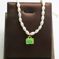 Close-up of pearl necklace with green suitcase pendant and Love Travels engraving - Green Suitcase Style / Green