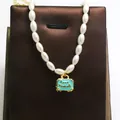 Detail view of a pearl necklace with a turquoise enamel suitcase pendant labeled Love Travels. - Mint Green Suitcase Style / Mint Green