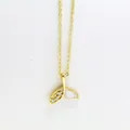 Close-up detail of a gold fish tail pendant necklace with rhinestones and white shell - Fish Tail Style