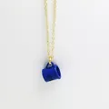 Close-up of blue coffee cup pendant necklace with engraved letter detail on gold chain. - Blue