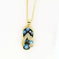 Detailed macro shot of a gold-toned flip-flop pendant featuring blue evil eye charms. - Black