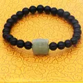 Macro detail of black obsidian beads and green nephrite jade tiger charm on bracelet - Obsidian