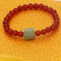 Detail of carnelian agate bracelet featuring an exquisite green jade tiger head charm. - Red Agate