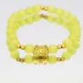 Detailed macro shot of yellow cat's eye bead bracelet featuring a cute golden dragon charm - Cat-eye Stone Bracelet / Light Yellow