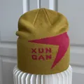 Nahaufnahme einer senfgelben Strickmütze mit pinkfarbenem Grafiklogo und Textverzierung - M / Kurkuma