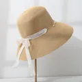 Detail of women's straw sun hat featuring elegant lace bow and delicate pearl accents - M (55-57.5) / Natural Straw with Beige Ribbon