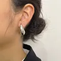 Detalle de un pendiente minimalista de metal plateado con forma de gota de agua - Pendientes de Botón de Gota de Agua Plateados (A5221_2)