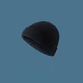 Close-up detail of a navy blue knitted brimless beanie on a solid blue background. - Elastic Adjustable / Black