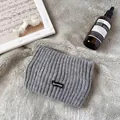 Nahaufnahme von grauem Rippstrick-Stirnband mit SSHIEE-Patch auf weichem Plüschhintergrund - Grau