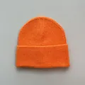 Detailed view of bright orange knit beanie showing soft wool-like texture and ribbed cuff. - One Size / Orange