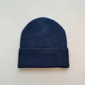 Nahaufnahme einer klassischen marineblauen Rippstrick-Beaniemütze für Winterwärme. - Einheitsgröße / Marineblau