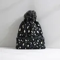 Detailansicht einer Strickmütze mit Leopardenmuster und einem großen weichen Bommel - Marineblau