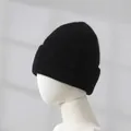 Nahaufnahme einer schwarzen Kaninchenfellmütze auf einem Mannequin mit Strickstruktur - Schwarz