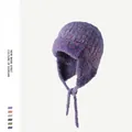 Dettaglio di un colbacco in maglia bouclé viola con paraorecchie e lacci intrecciati. - Taglia unica / Viola