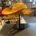 Detailansicht eines orangefarbenen Outdoor-Sonnenhutes mit Logo auf einem Ständer - M (56-58cm) / Orangegelb