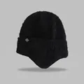 Detail view of a black fuzzy knit earflap hat featuring a small white snowflake patch - Elastic Circumference (56-59cm) / Black