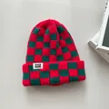 Nahaufnahme der rot-grün karrierten Strickmütze mit weißem Markenaufnäher - Elastischer Umfang / Rot Kariert