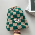 Detailansicht einer grün-beigen karierten Strickmütze mit einem weißen Markenetikett - Elastischer Umfang / Grünes Karo