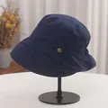 Side detail of a navy blue pleated bucket hat with a small decorative metal tag. - Adjustable (56-58cm) / Blue
