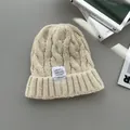 Dettaglio macro di un berretto in maglia a trecce crema con etichetta di moda bianca cucita - Albicocca