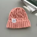 Vista dettagliata di un berretto rosa in maglia a trecce con etichetta tessuta bianca. - Rosa chiaro