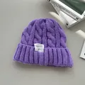 Vista dettagliata di un berretto in maglia a trecce viola con etichetta bianca moda. - Viola