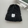 Dettaglio del berretto in maglia a trecce nero con etichetta moda bianca per l'inverno - Nero