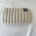 Close-up of a vintage cream ribbed knit wide headband featuring a black logo label - Off White