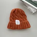 Vista dettagliata di un berretto arancione lavorato a trecce con etichetta moda bianca - Colore caramello